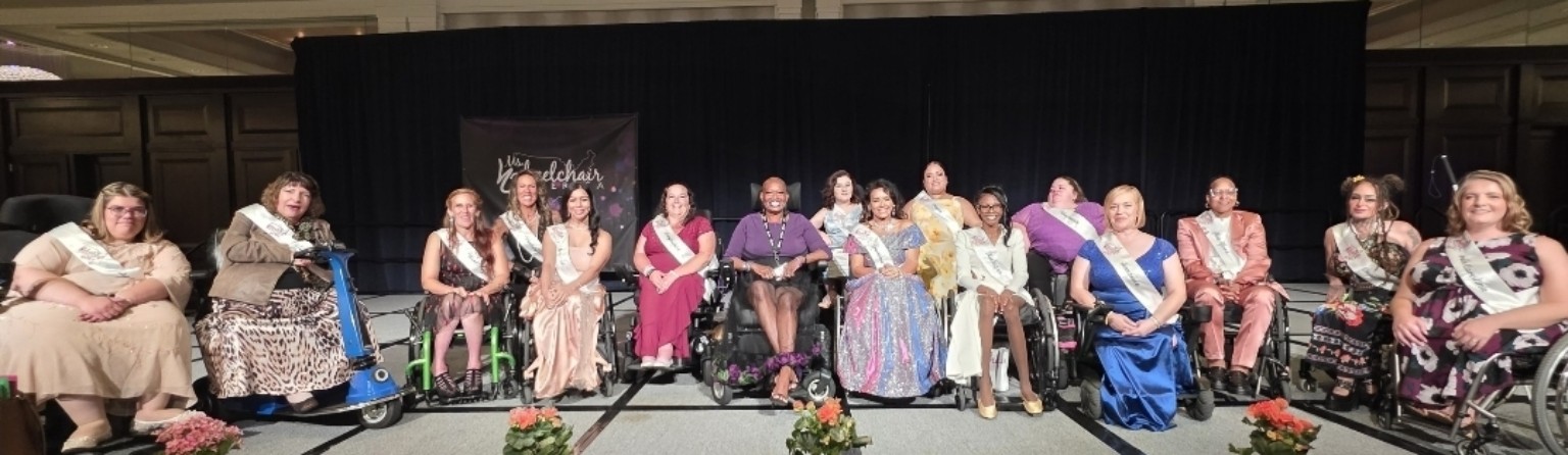 Dr. Kimberly, seated near the center in purple, joins Ms. Wheelchair America contestants in a wide group photograph onstage.