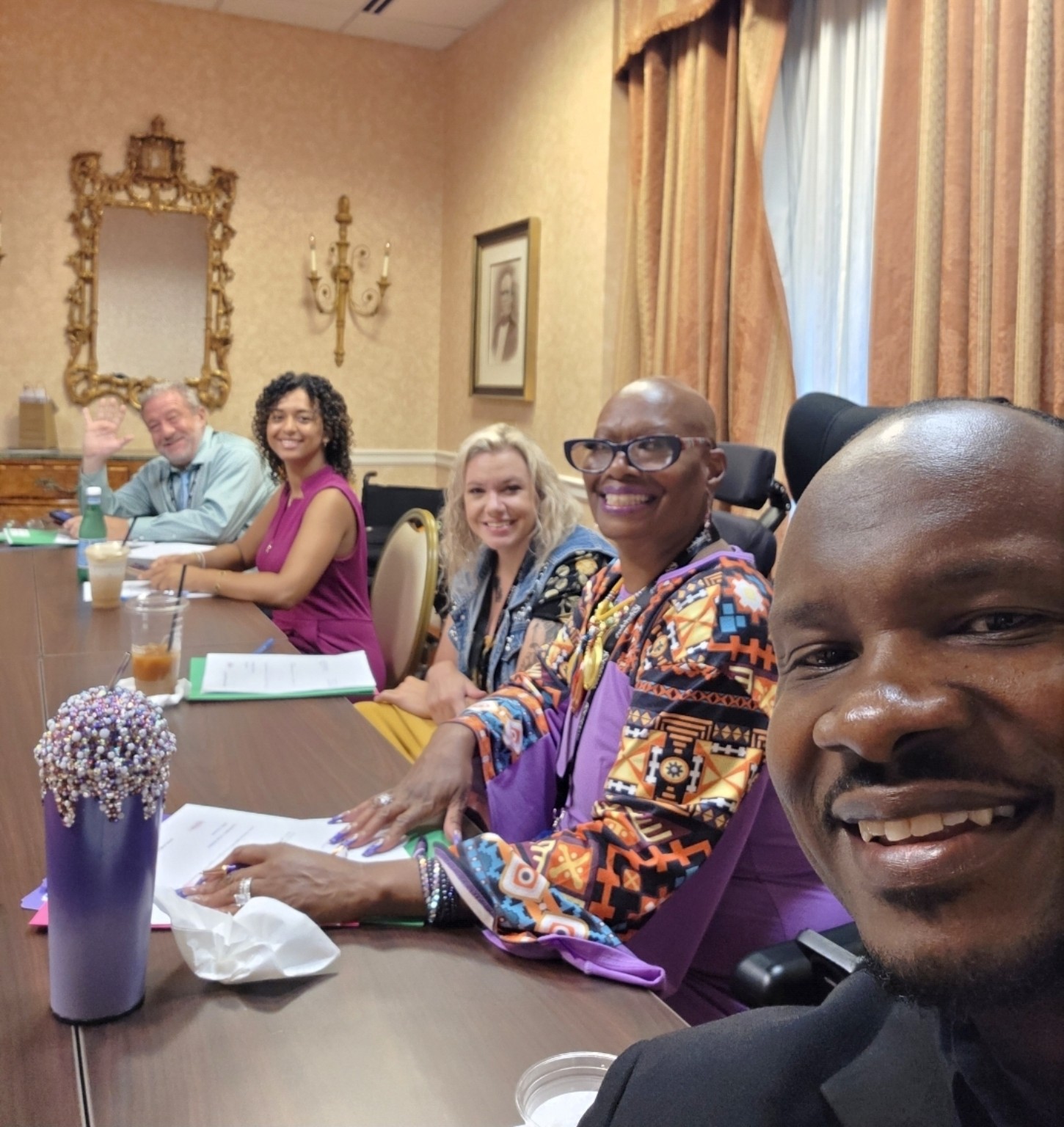 Dr. Kimberly smiles with her fellow Ms. Wheelchair America judges around a meeting table.