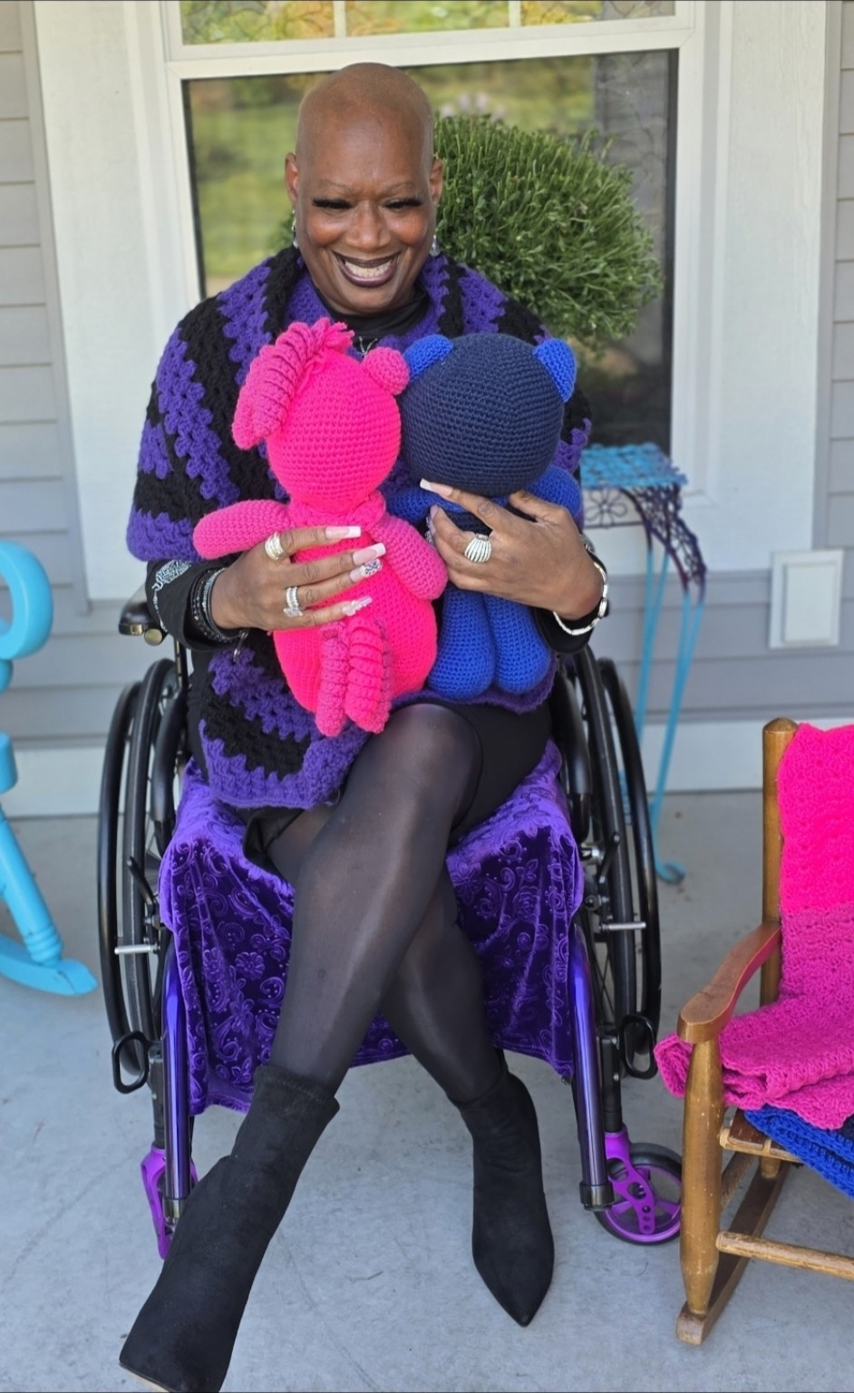 Dr. Kimberly holds Shana’s pink and blue crocheted bears with their backs facing the camera, showing the texture and details of the handmade pieces.